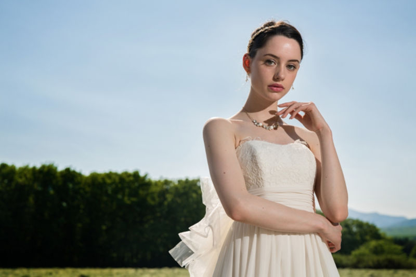 Amostra de imagem de uma mulher usando um vestido branco com uma floresta ao fundo