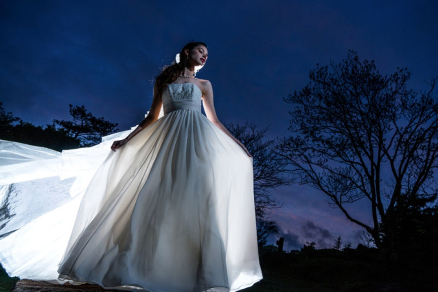 Amostra de imagem de uma mulher em um vestido branco à noite, com árvores ao fundo